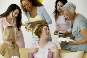 Group of women admiring gifts at baby shower, smiling