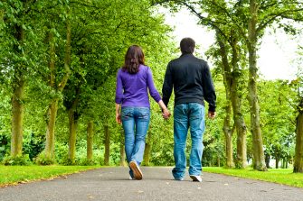 couple holding hands and walking in a park